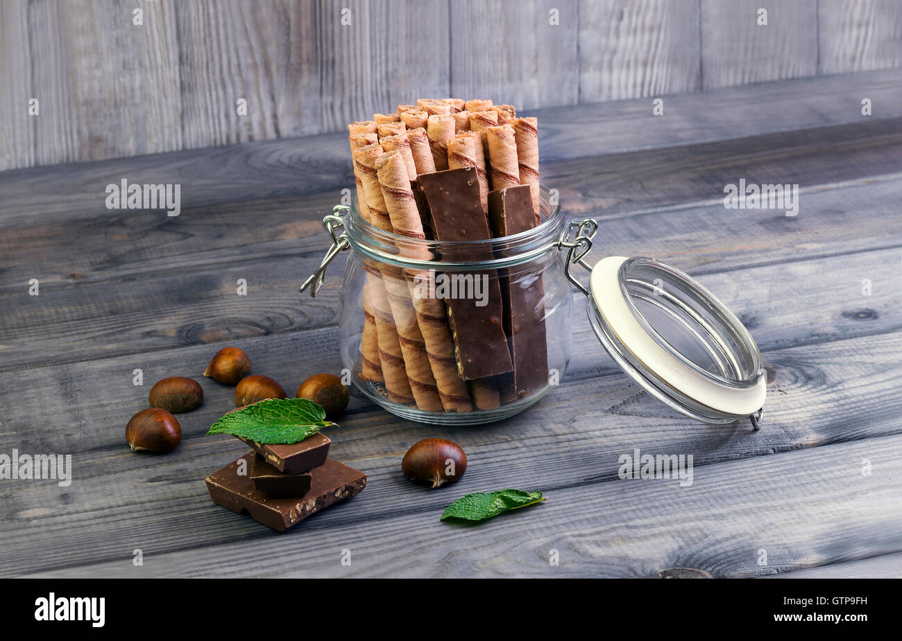 On a wooden table in vintage style glass jar with wafer rolls, slices ...