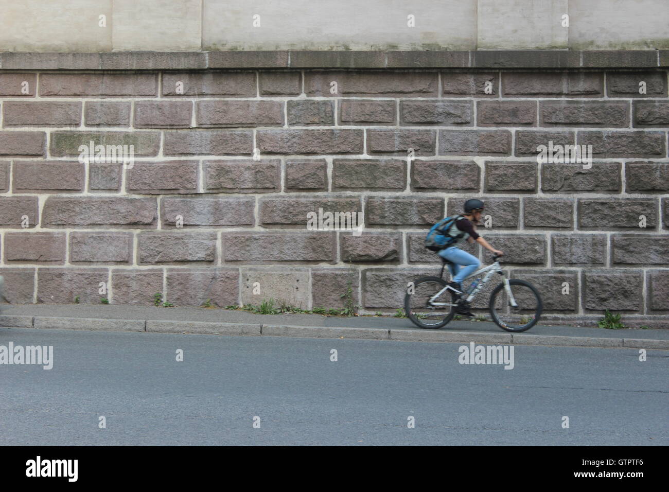 boy cycling in front of a stone wall Stock Photo
