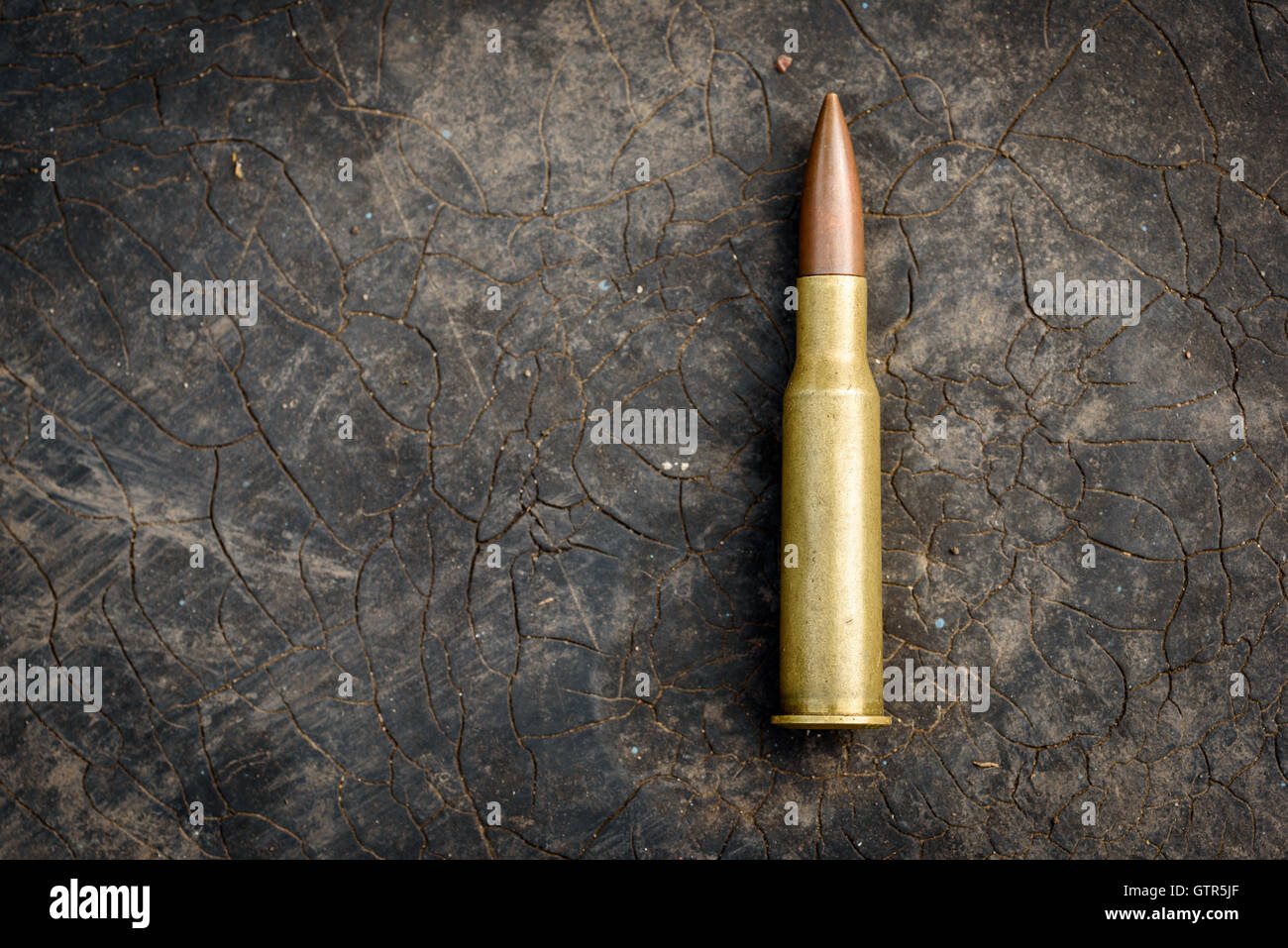 Single 7.62mm bullet with brass shell casing. Unfired ammunition for modern assault rifles like the AK-47 Kalashnikov on a black Stock Photo