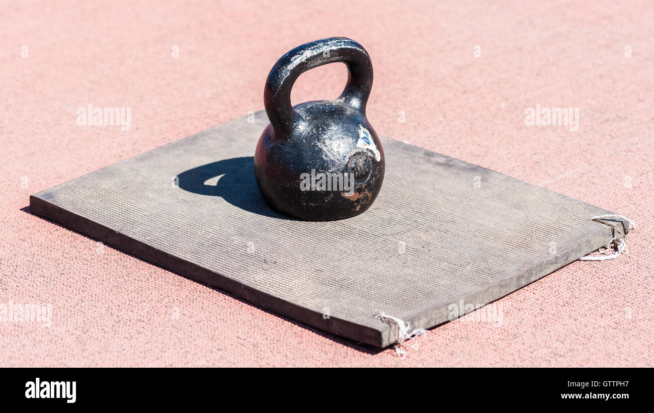 Heavy iron dumb bell on a rubber mate on a brown textured surface. This is 16 kilograms or 35.3 pounds weight Stock Photo