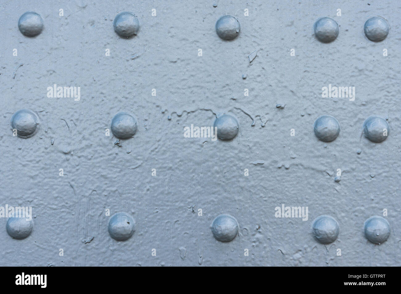 Bluish gray painted metal surface with three rows of rivet heads. Texture or background theme. Stock Photo