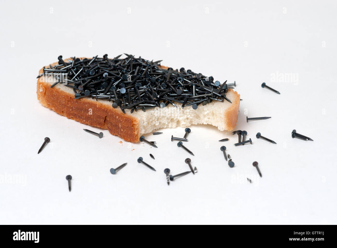 Open sandwich made of white bread and black shoe nails or tacks. Yogi snack. Surreal meal. Isolated against white background. Stock Photo