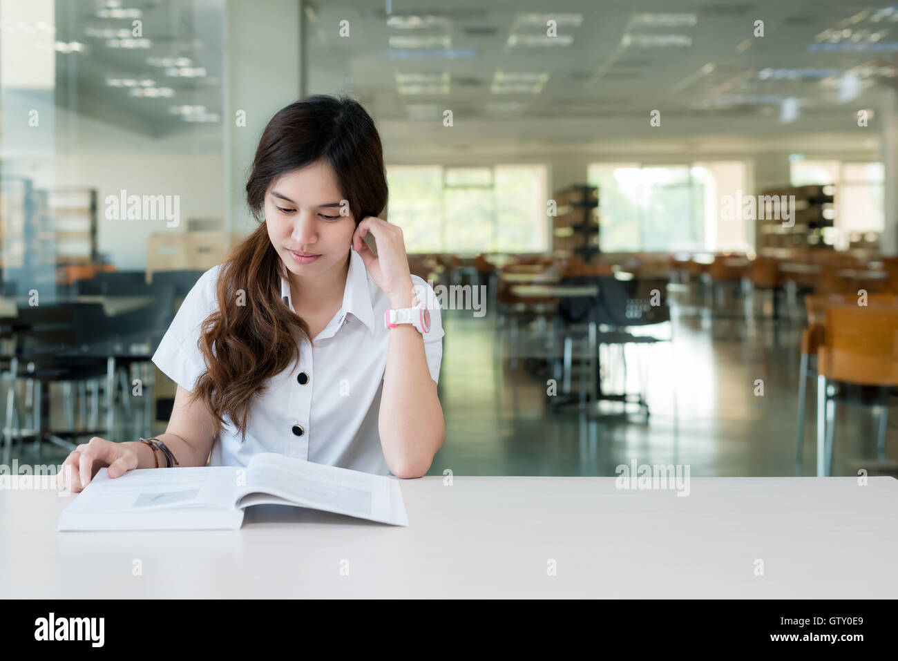 Asian student in uniform reading book for learning in classroom at university.One Asian student. Stock Photo