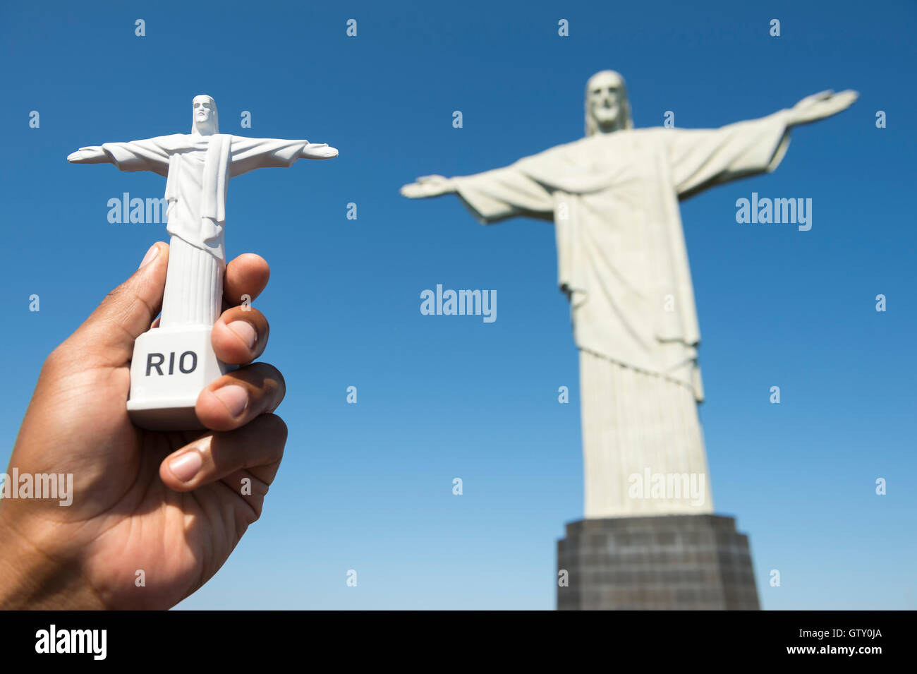 RIO DE JANEIRO - MARCH 05, 2016: Hand holding tourist souvenir in front of Statue of Christ the Redeemer at the top of Corcovado Stock Photo