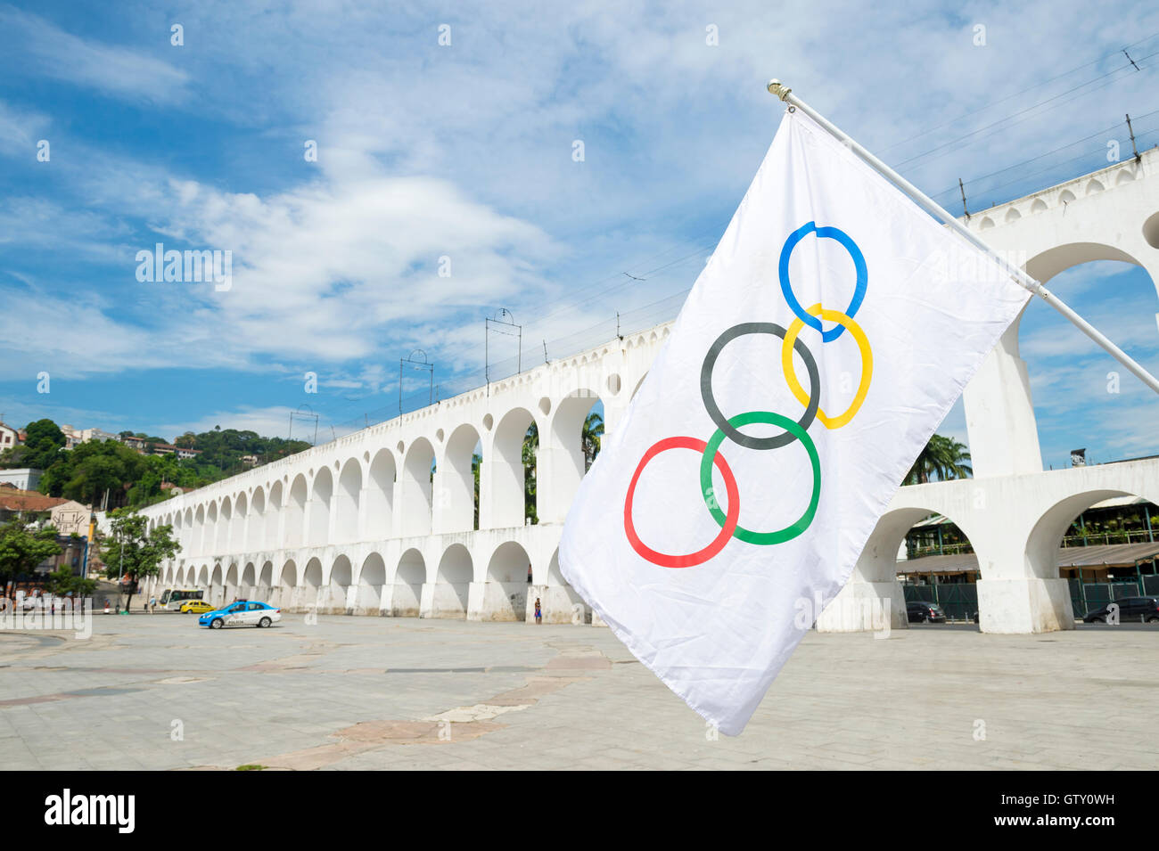 RIO DE JANEIRO - MARCH 6, 2016: An Olympic flag flies in the plaza above the famous Arcos da Lapa Arches landmark. Stock Photo