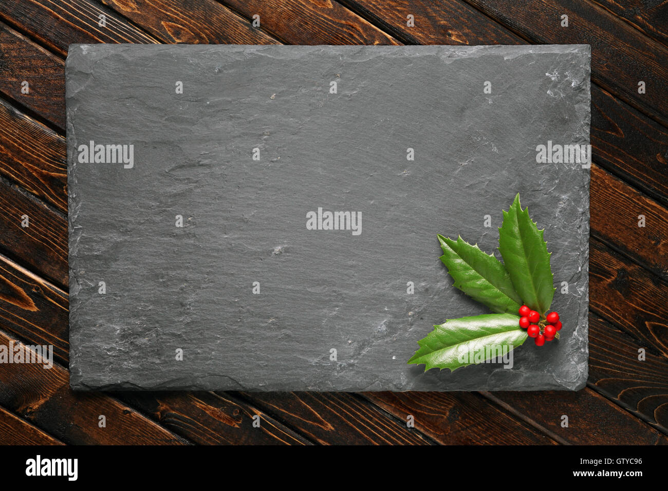 Holly with berries on dark stone background Stock Photo