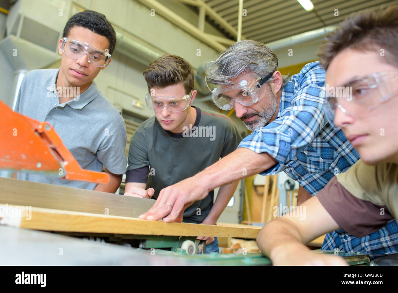 Carpenter showing apprentices how to use machinery Stock Photo Alamy