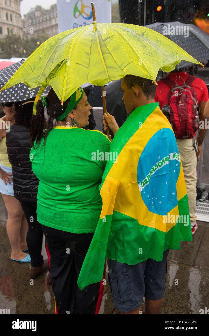 People shelter from the rain in Trafalgar Square, London, during Brazil Day 2016, a celebration of the Rio 2016 Olympic and Paralympic games and Brazilian culture. Stock Photo