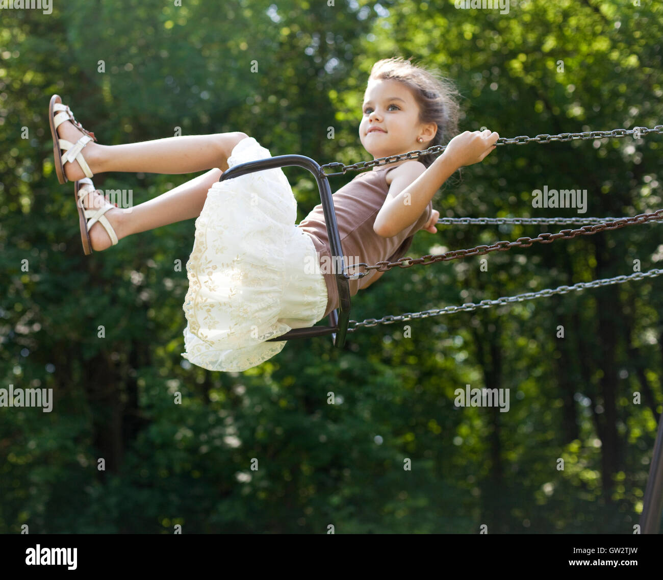 Happy little girl riding on a swing in the park Stock Photo - Alamy
