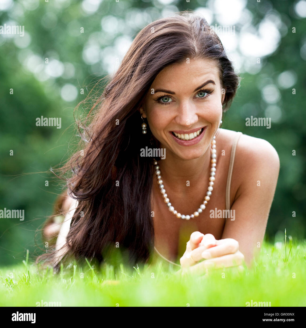 Portrait of young woman lying on a green lawn Stock Photo - Alamy