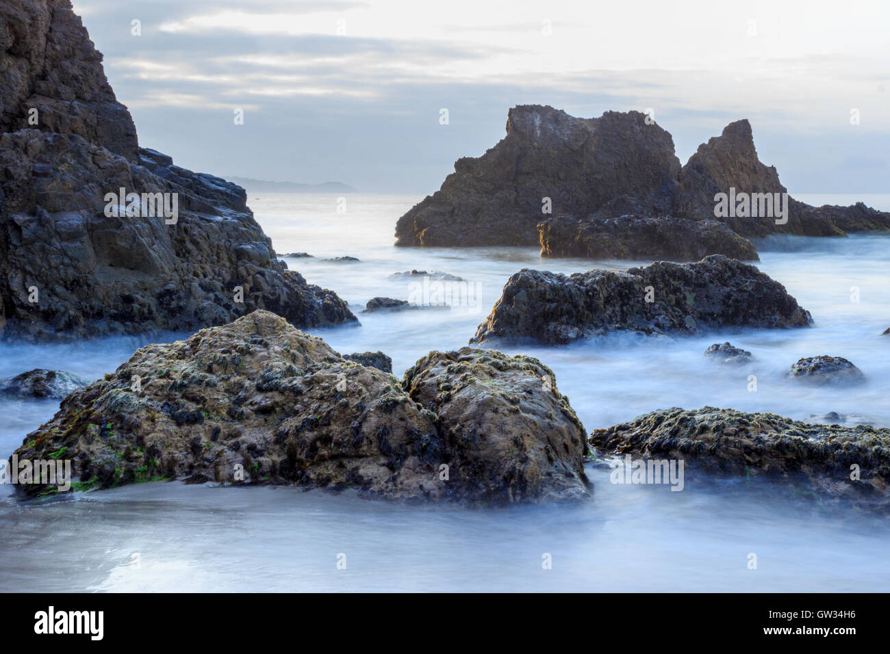 waves surrounding jagged rocks in Malibu Stock Photo