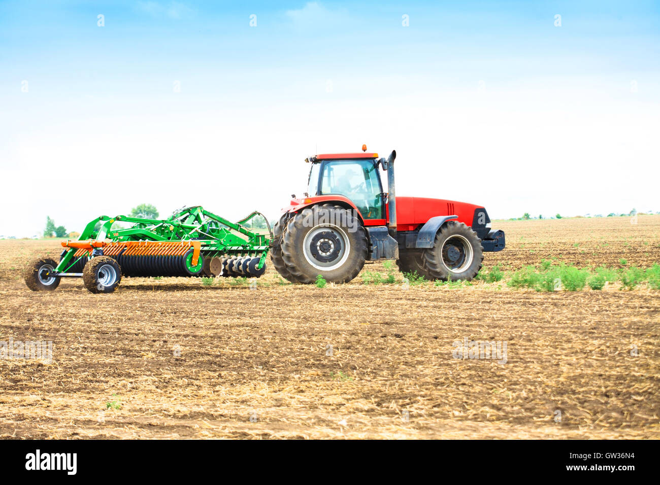 Tractor with a harrow to work the land field Stock Photo - Alamy