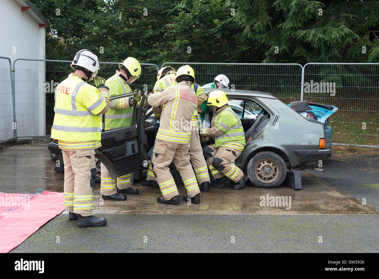 Fire men simulate a car crash rescue by cutting the doors off the car. Stock Photo