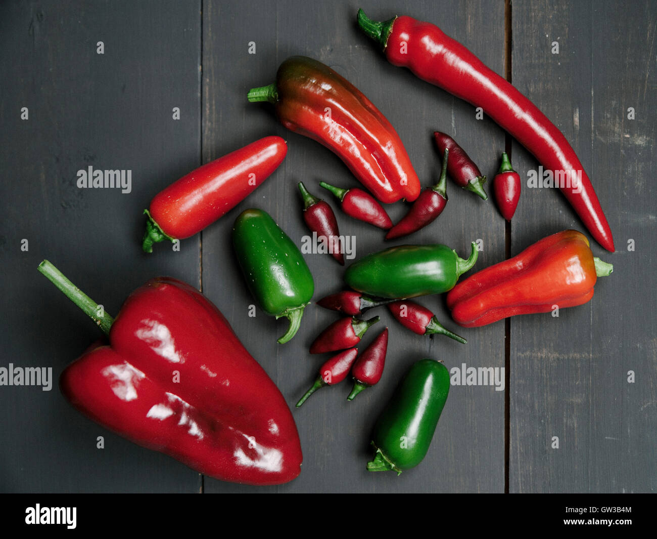 Red and green chili peppers on a dark wood background Stock Photo - Alamy