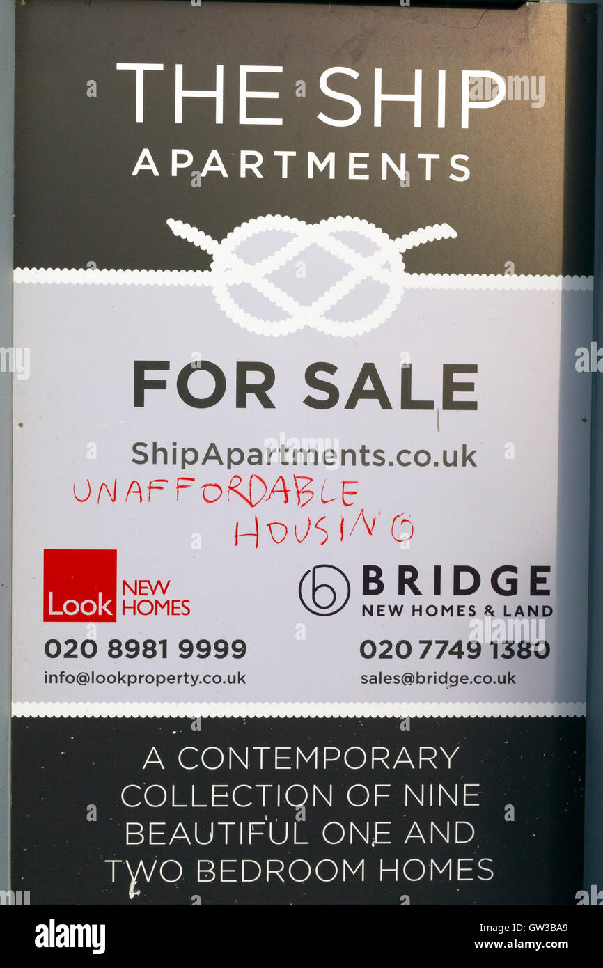 Unaffordable Housing scrawled across a The Ship London Apartments For Sale poster, Cable Street, London, UK Stock Photo