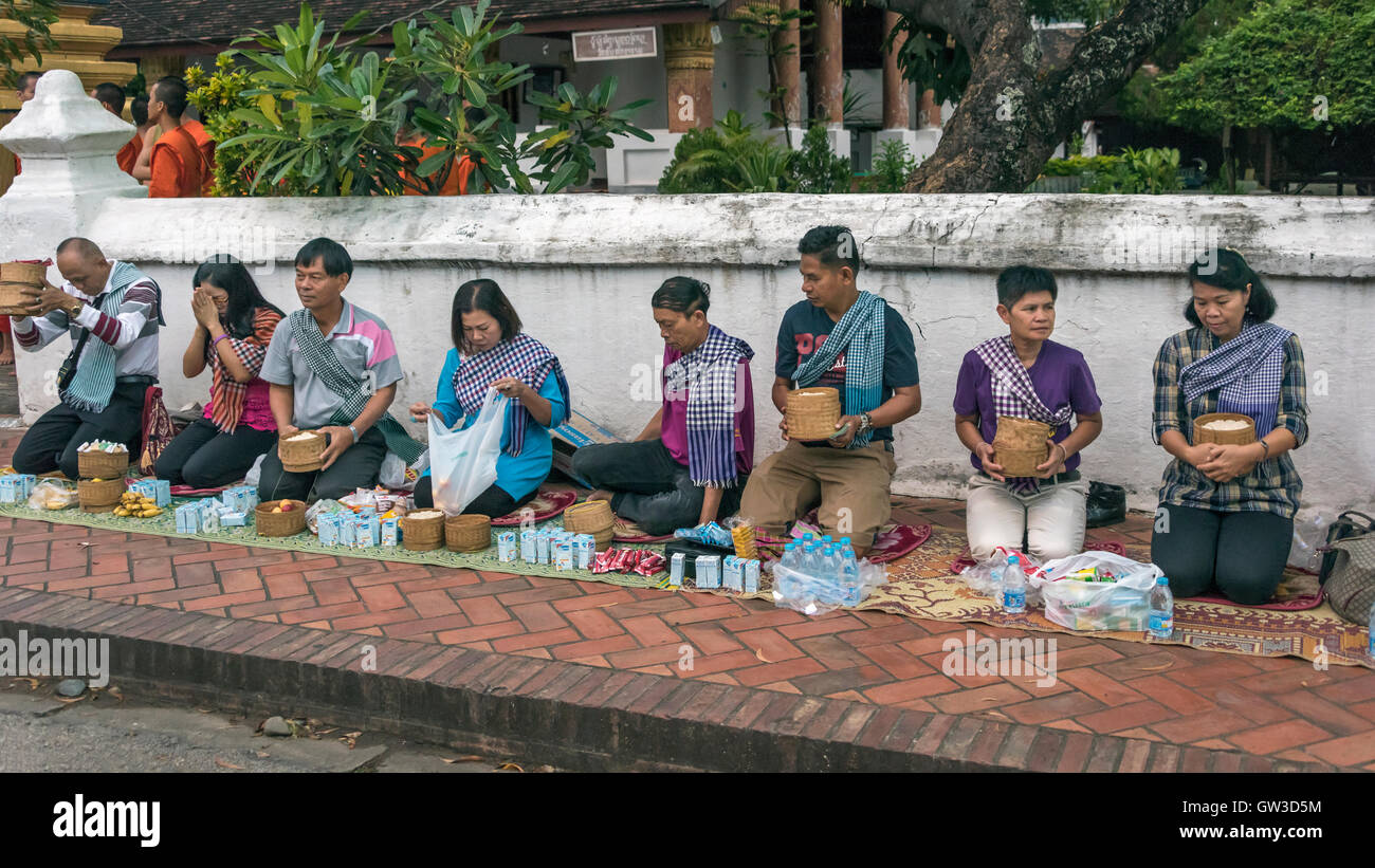 Local people line-up to give alms to the Buddhist monks, Sisavang Vong Road, Luang Prabang, Laos Stock Photo