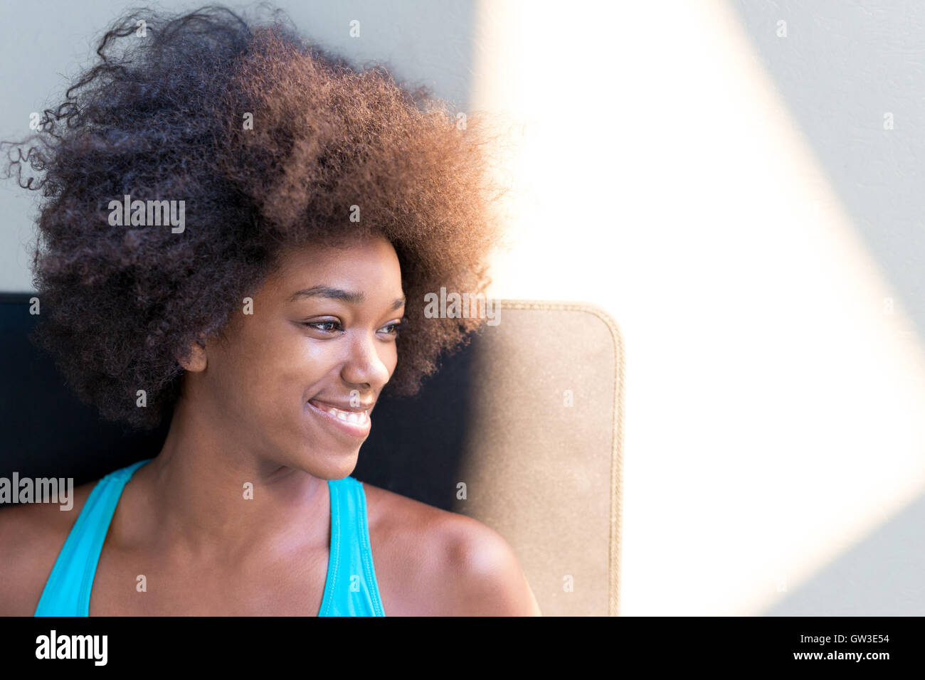 Young happy woman sitting on the mat having a rest after fitness ...