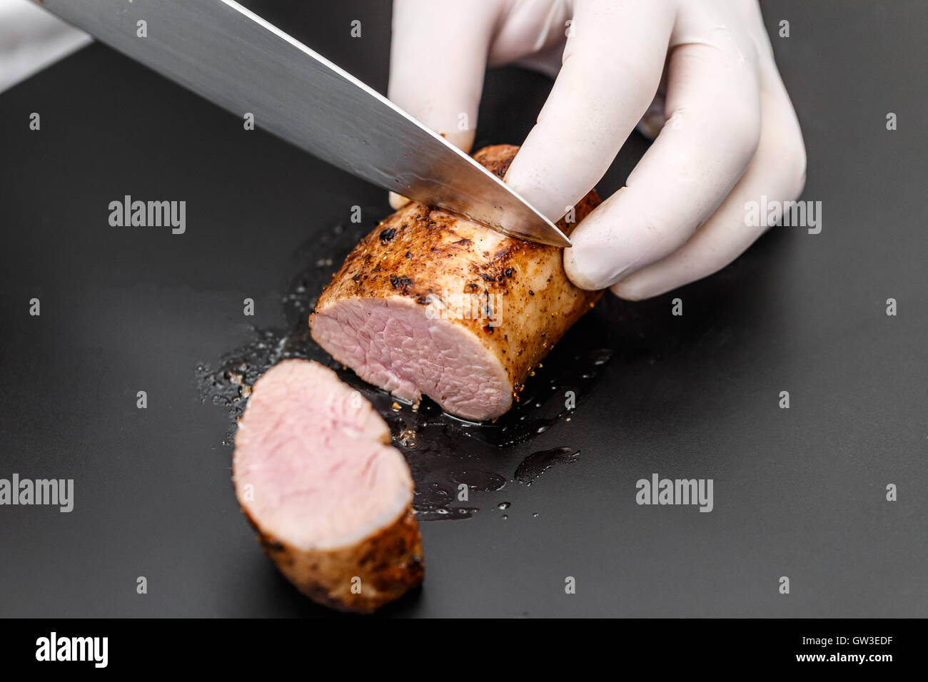 Premium Photo  Man cuts of fresh piece of meat on a wooden cutting board  in the home kitchen. a man in a striped apron with a big knife in his hands