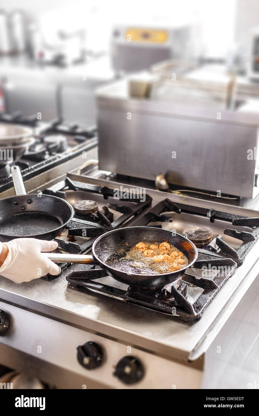 Professional chef in a commercial kitchen cooking flambe style. Stock Photo