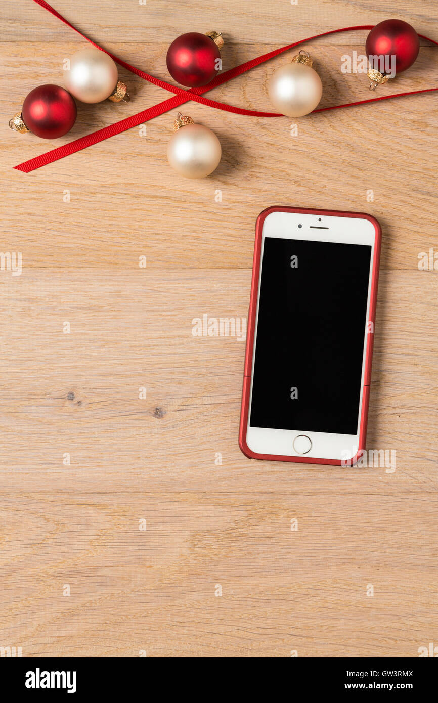 Cell phone iPhone 6 with festive holiday Christmas decorations on rustic wood background Stock Photo