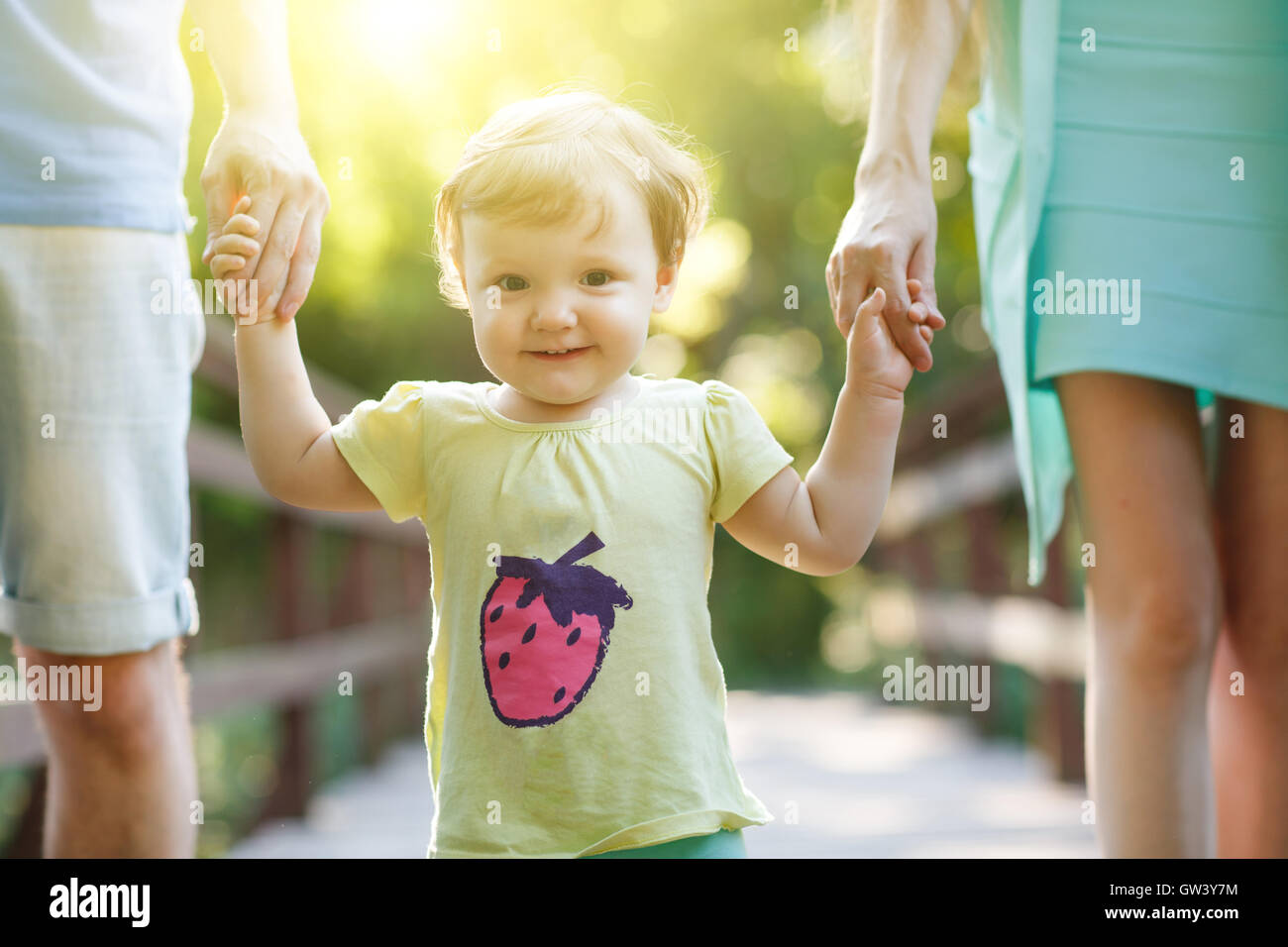 Parents holding little girl for hands in summer park Stock Photo - Alamy