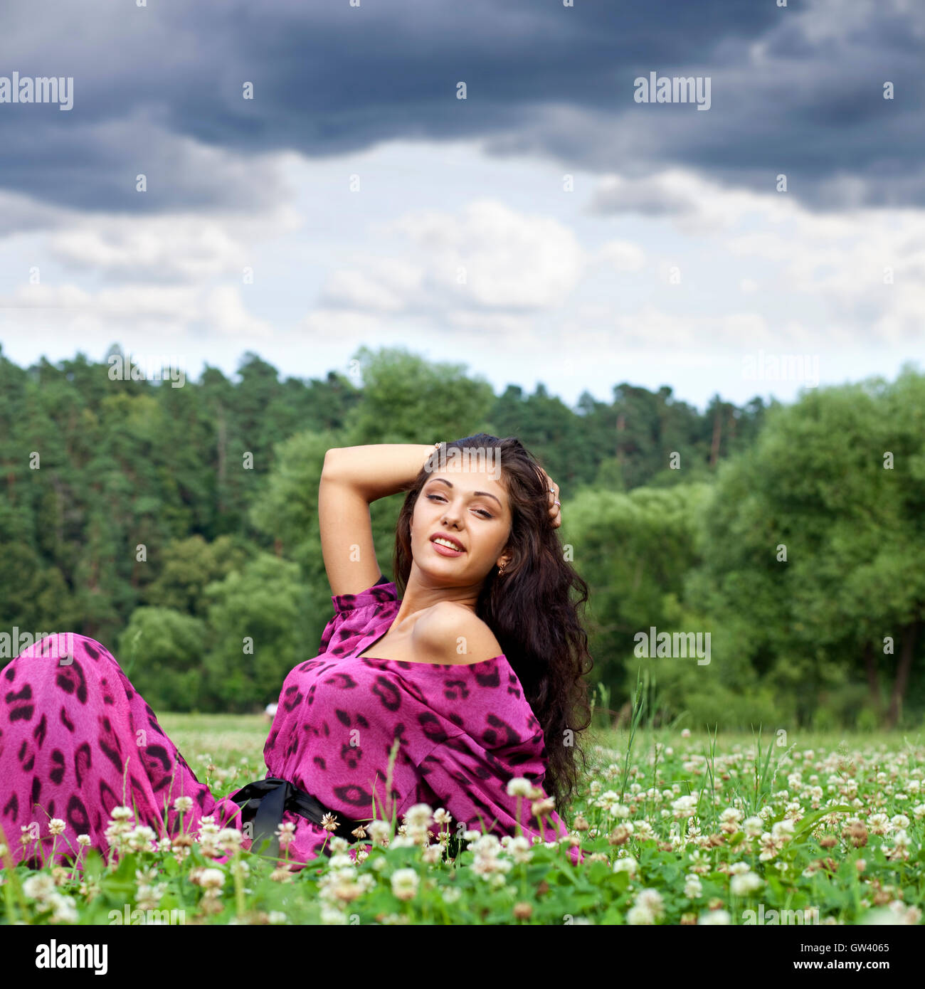 Portrait of young woman sitting on a green lawn Stock Photo - Alamy