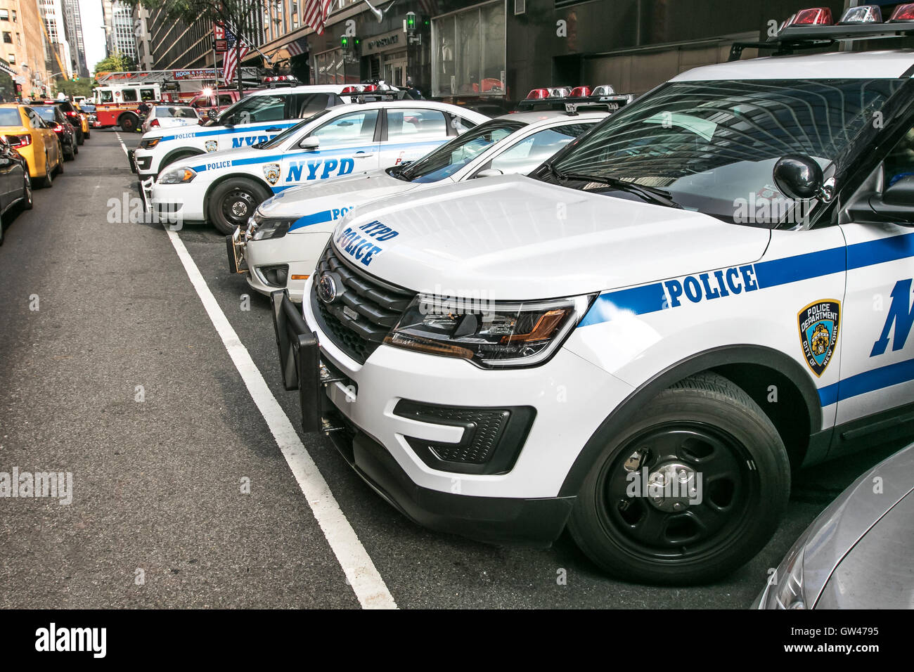 Police cars parked near a precinct in New York City. A fire truck is coming out on the street in the background. Stock Photo