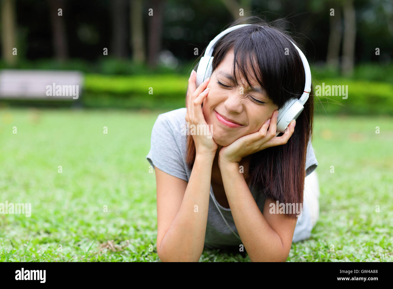 Asian woman listen to song lying on grass Stock Photo - Alamy