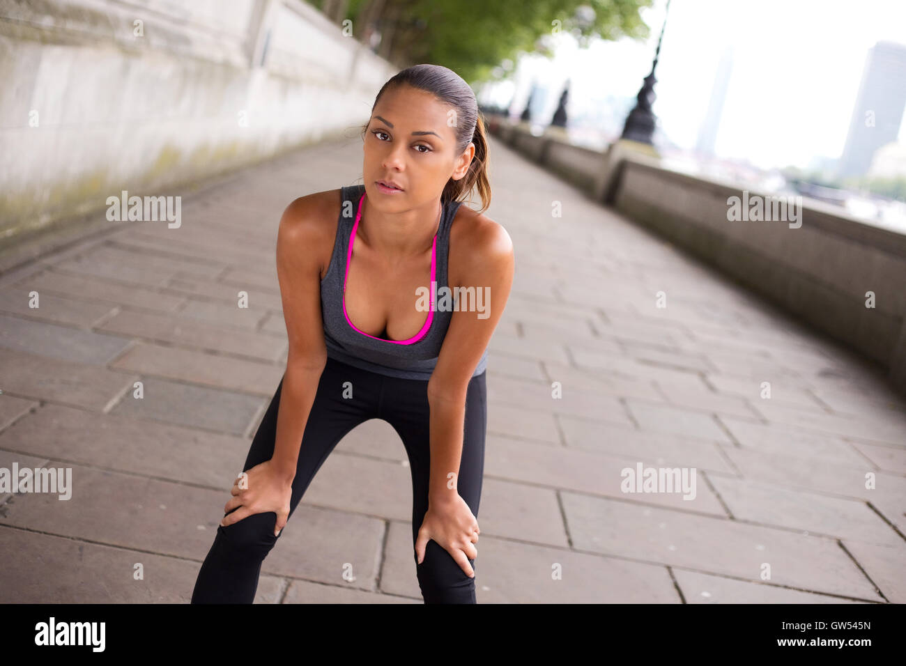 Runner leaning over to catch her breath Stock Photo Alamy