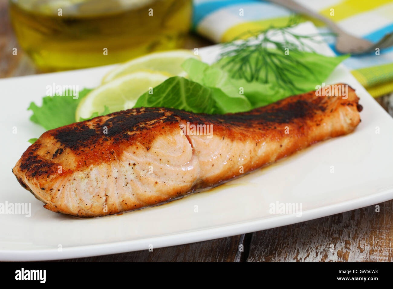 Grilled salmon steak with green salad and lemon on white plate Stock Photo