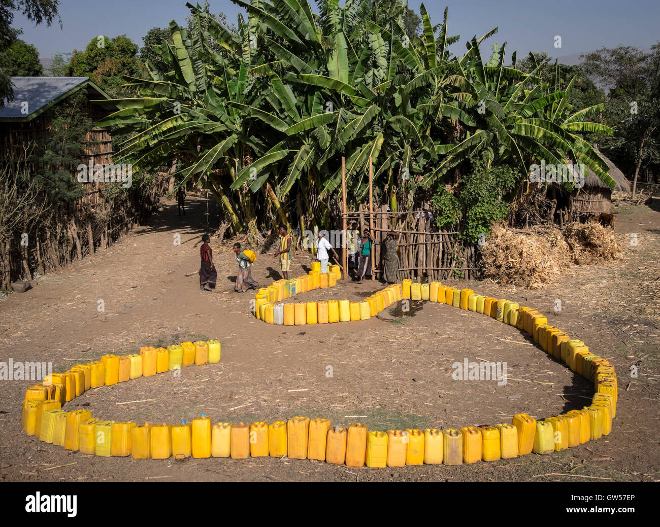 Villagers line up their water cans waiting for water from the village well in the Omo Valley of Ethiopia Stock Photo