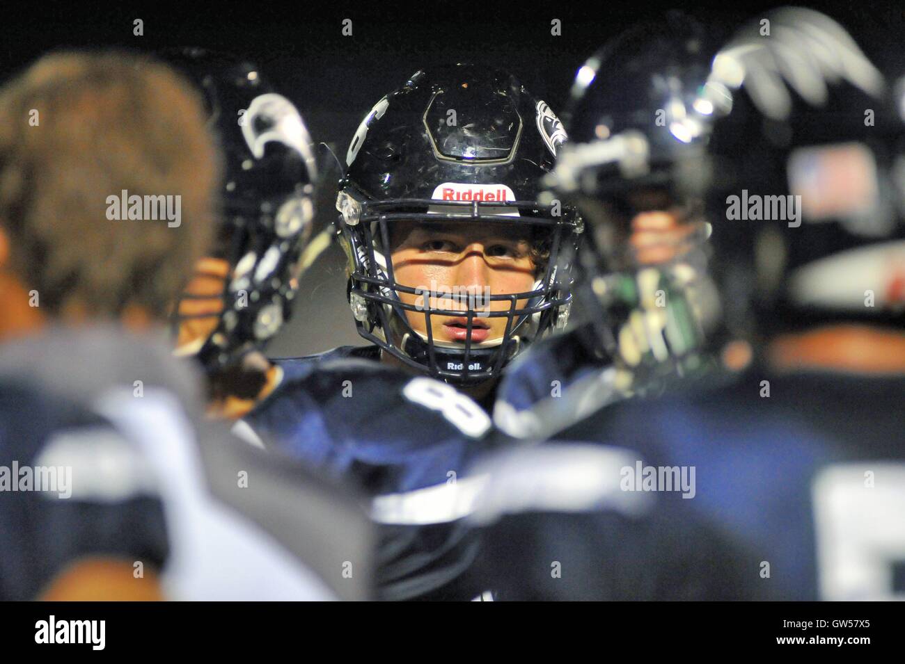 Player within a huddle totally focused on the direction of a coach during a high school football game. USA. Stock Photo