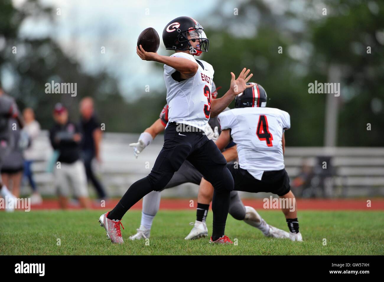 After rolling out of the pocket, a quarterback throws a pass down field during a high school