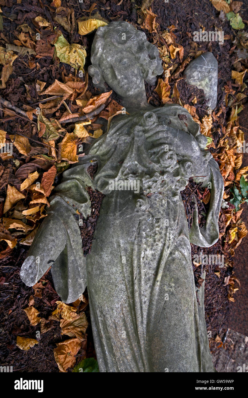 Figure of a broken angel surrounded by Autumn leaves in Morningside Cemetery, Edinburgh, Scotland, UK. Stock Photo