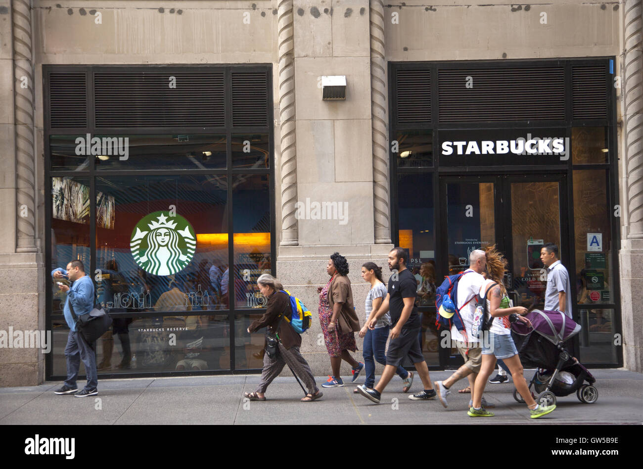 Pedestrians scurry by one of the countless Starbucks in Manhattan, New York City. Stock Photo