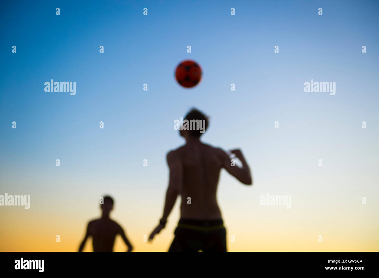 Brazilian beach footvolley game played in defocus silhouette against the sunset sky in Rio de Janeiro, Brazil Stock Photo