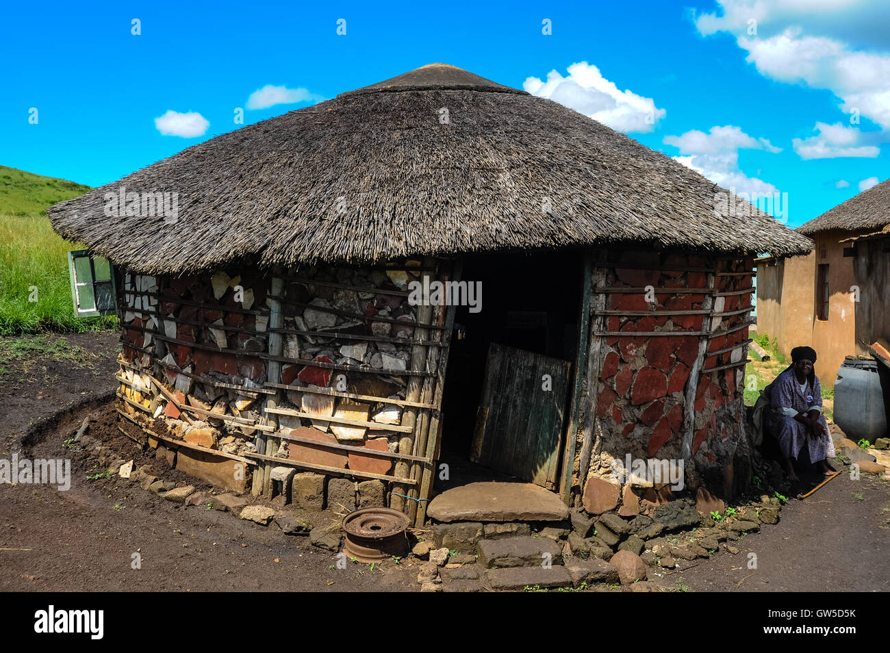 Visiting a small Zulu village near Hluhluwe in the KwaZulu-Natal province, South Africa. An old lady sitting outside the kitchen. Stock Photo