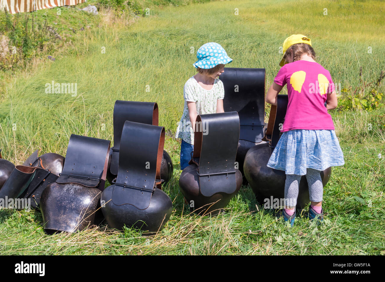 Two pre-teen girls playing with large 'Trychlen', hammered sheet-metal cowbells popular in Switzerland. Stock Photo