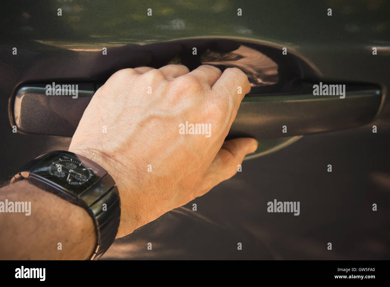 Male hand with wrist watch opens car door, closeup photo with selective focus Stock Photo