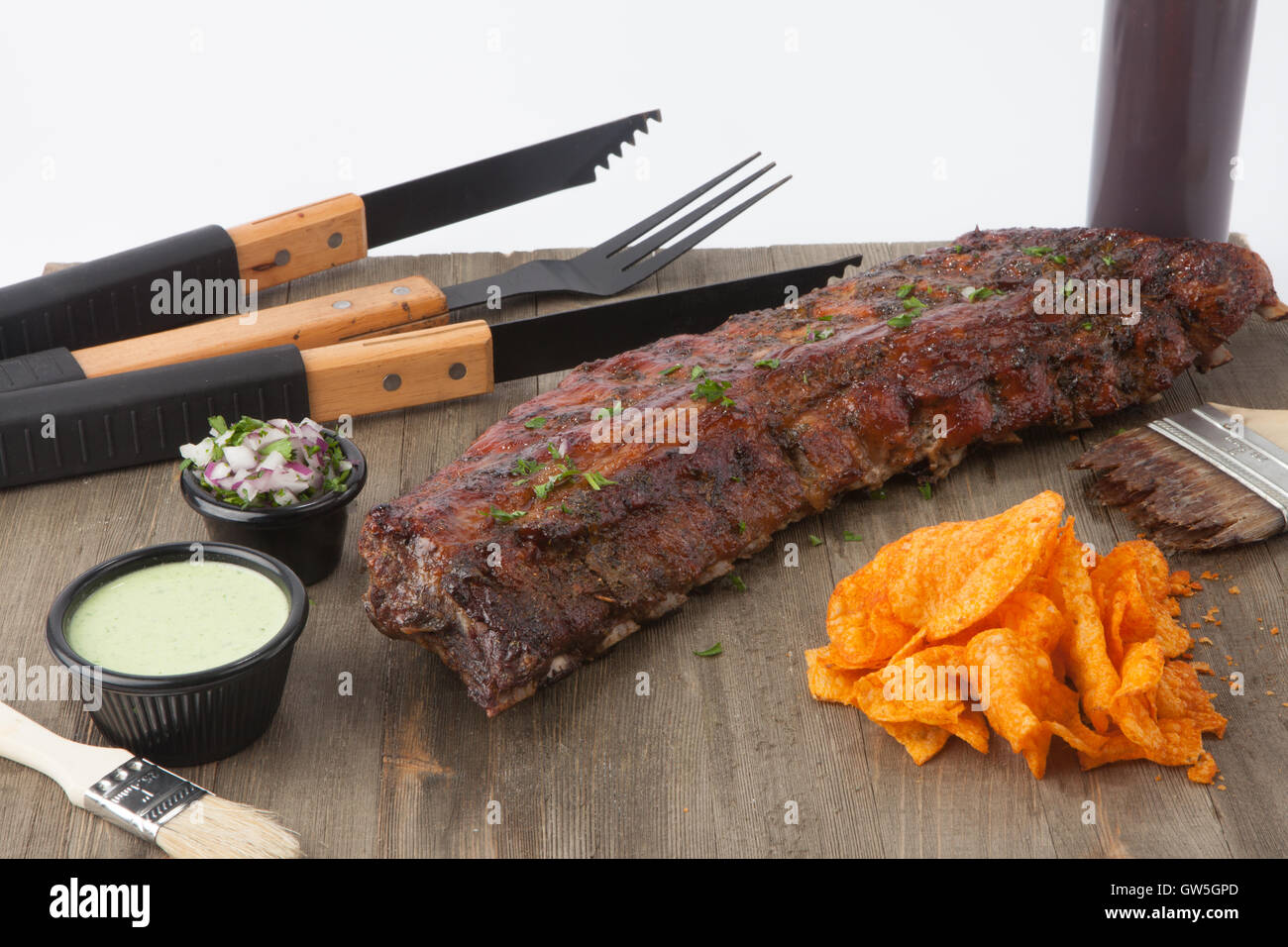 Full rack of ribs with cilantro sauce bbq sauce bottle standing, onions and parsley Stock Photo