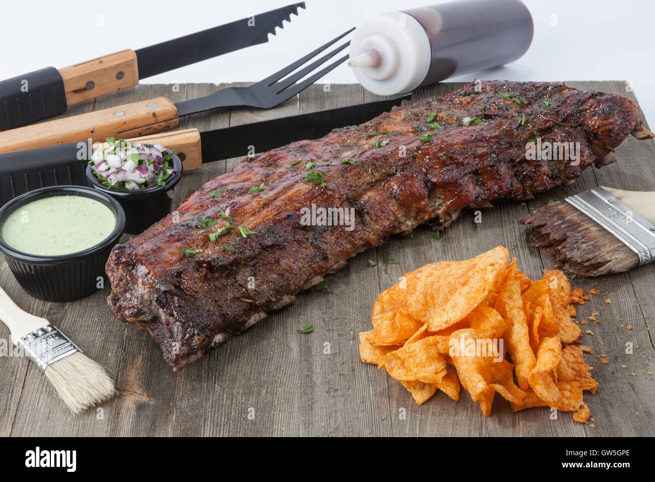 Full rack of ribs with cilantro sauce bbq sauce bottle, onions and parsley Stock Photo