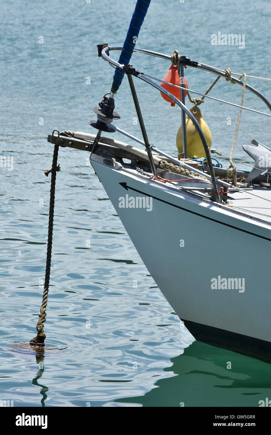 Ship bow with mooring rope disappearing under calm sea surface. Stock Photo