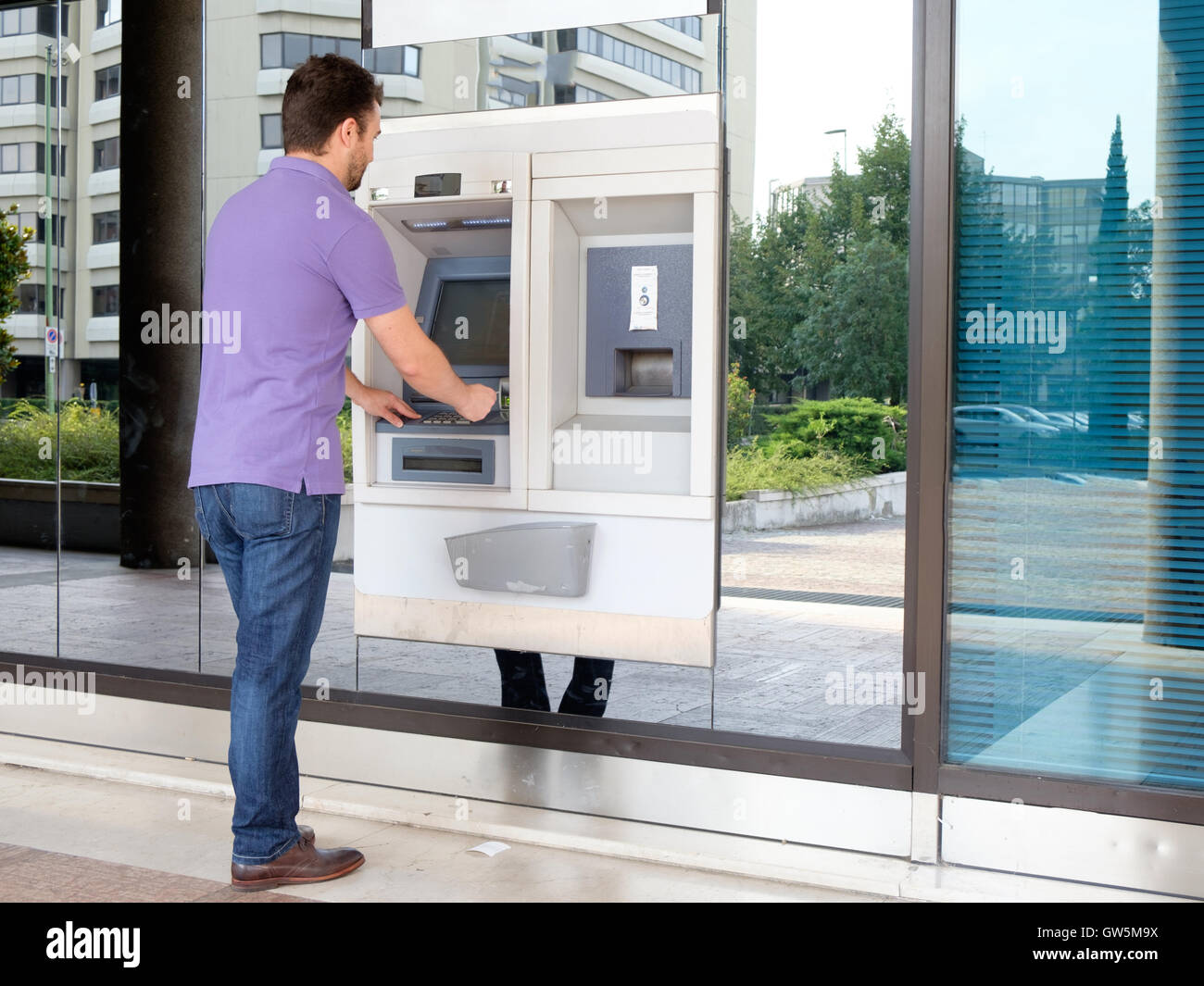 Man using his credit card in an atm for cash withdrawal Stock Photo