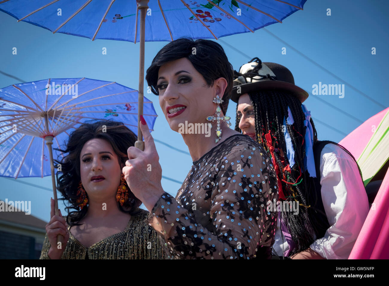 Three drag queens with umbrellas aboard a float in preparation for a Carnival parade in