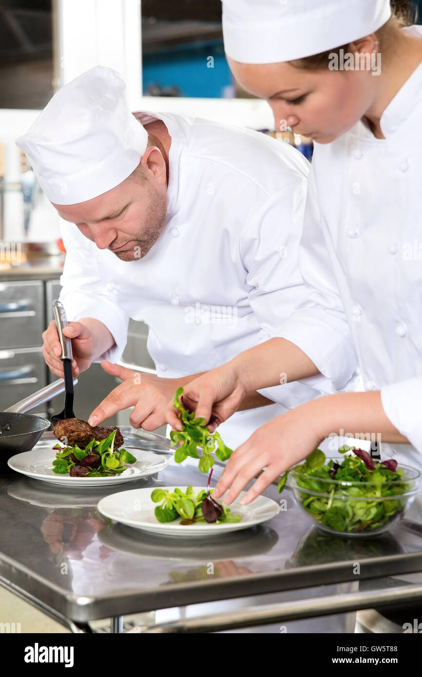 Two dedicated chefs prepares steak dish at gourmet restaurant Stock Photo