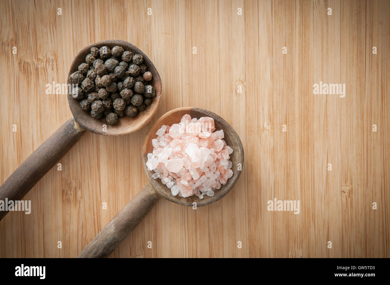 Salt and pepper seasonings of pepper corns and rock salt on wooden spoons Stock Photo