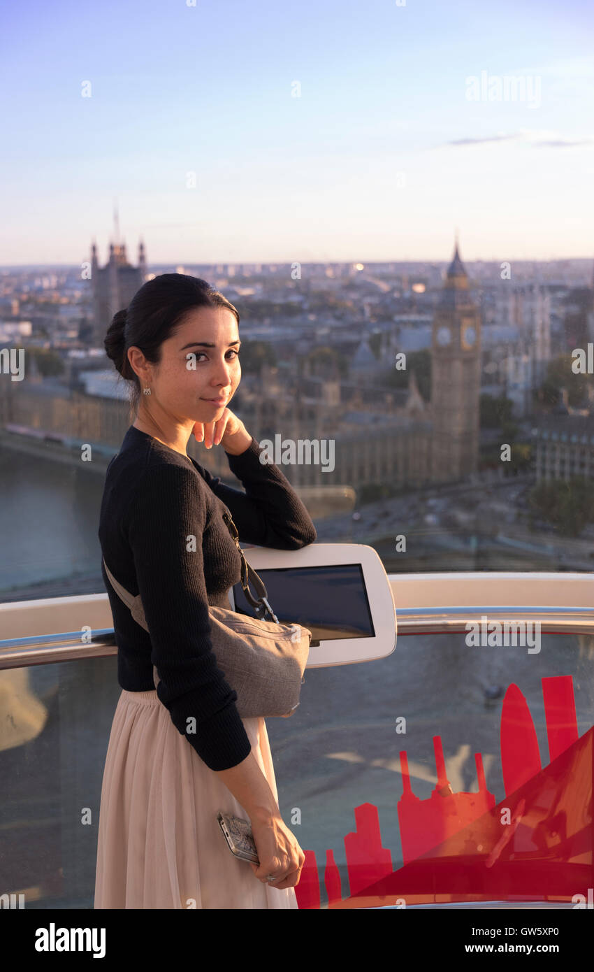 Woman inside a cabin of the London Eye ferris wheel overlooking the Thames River and Houses of Parliament, London, England. Stock Photo
