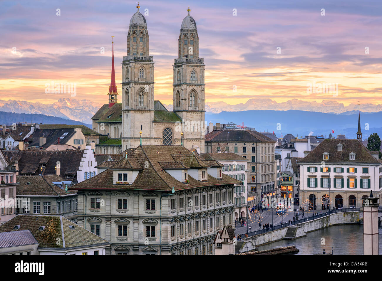 Zurich city center and cathedral towers with snow covered Alps mountains in background on sunset, Switzerland Stock Photo