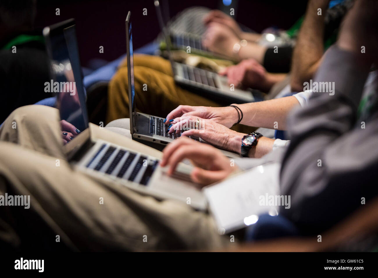 a row of people using Apple MacBooks during a conference Stock Photo