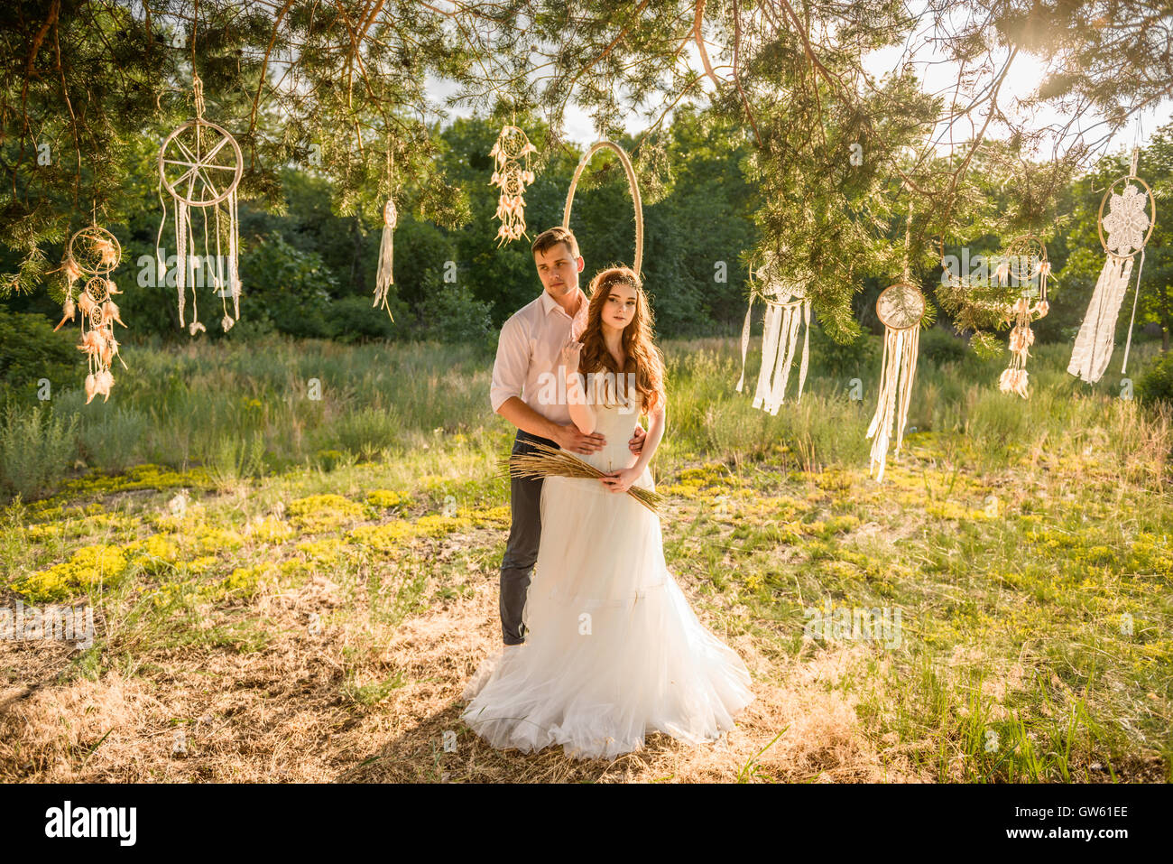 bride and groom posing near the charms in a tree in the forest. Wedding ...